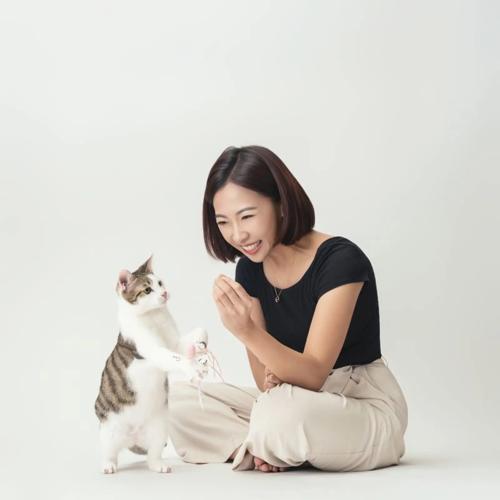 獸醫師 Emily 蹲下與貓互動，貓伸手回應